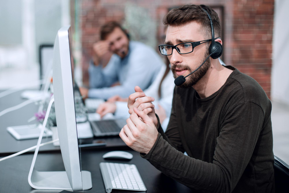 man-with-headset-sitting-by-computers-bright-officephoto-with-copy-space